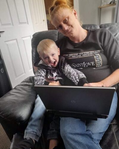 Lady and son sat down looking at laptop in a home