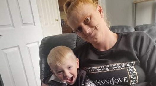 Lady and son sat down looking at laptop in a home